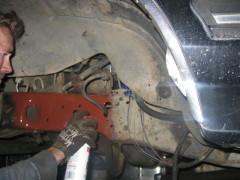 1989 Ford Bronco - Photo of a person working under a vehicle near a red bracket, not a technical document.