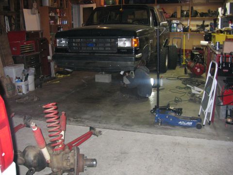 1989 Ford Bronco - Photo of a black Ford truck in a garage with a coil spring suspension part in front, not a document.