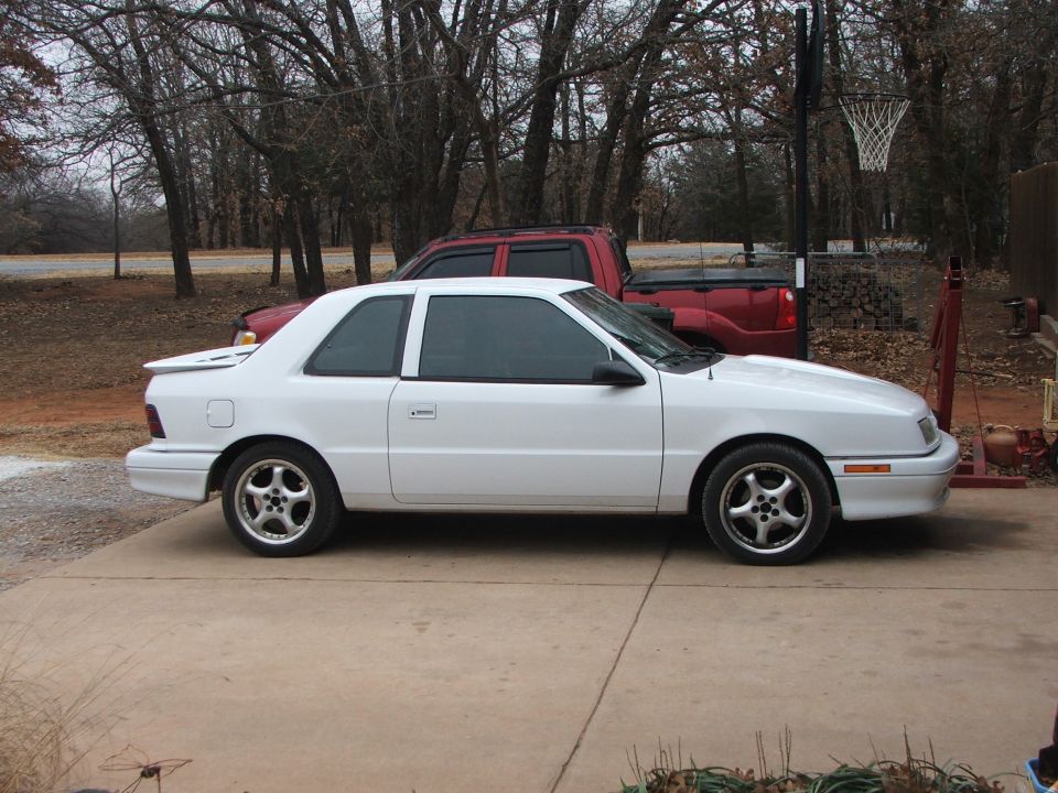 White 1990 Dodge Shadow coupe parked on concrete driveway.