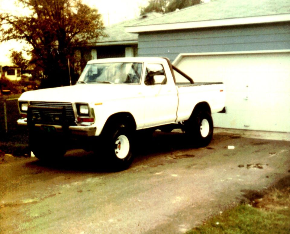 Vintage white lifted Ford pickup with roll bar in a driveway