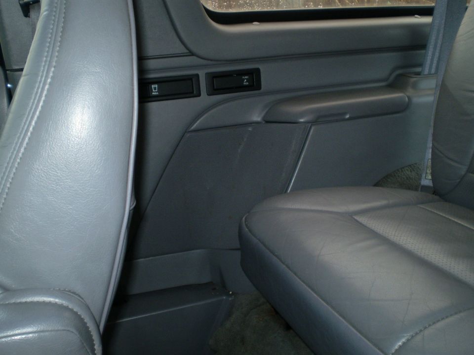 Interior of a vehicle showing gray leather seats and door panel with two compartments.