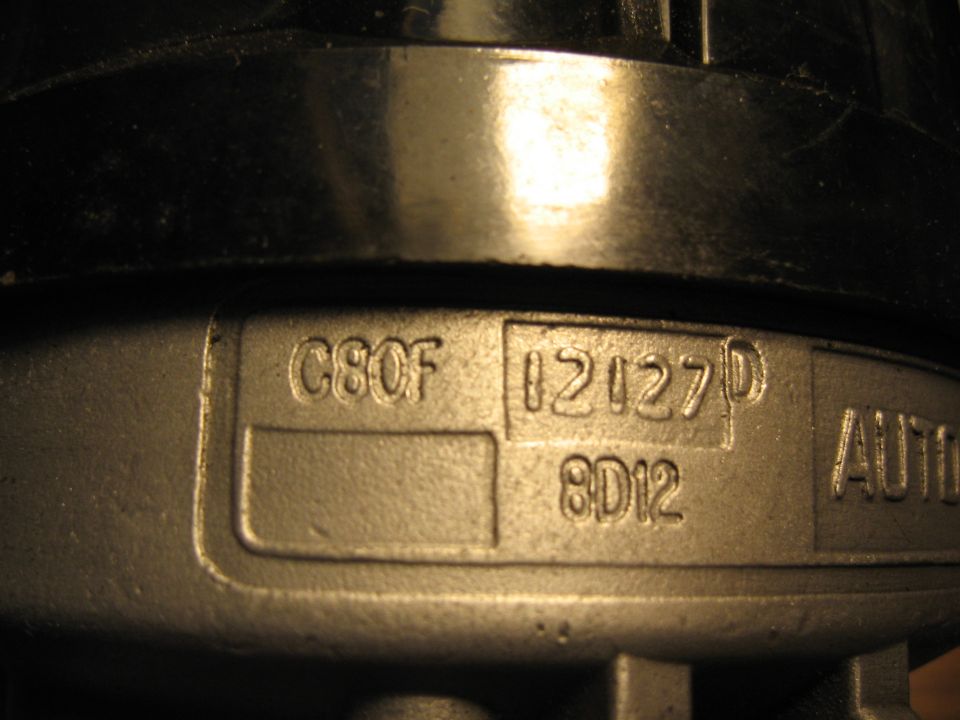 Close-up of stamped metal part with text C8OF 12127D 8D12 AUTO