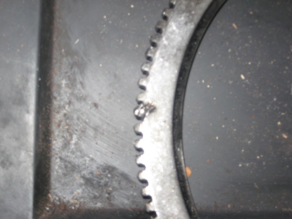 Close-up of flywheel ring gear teeth with chipped, damaged teeth