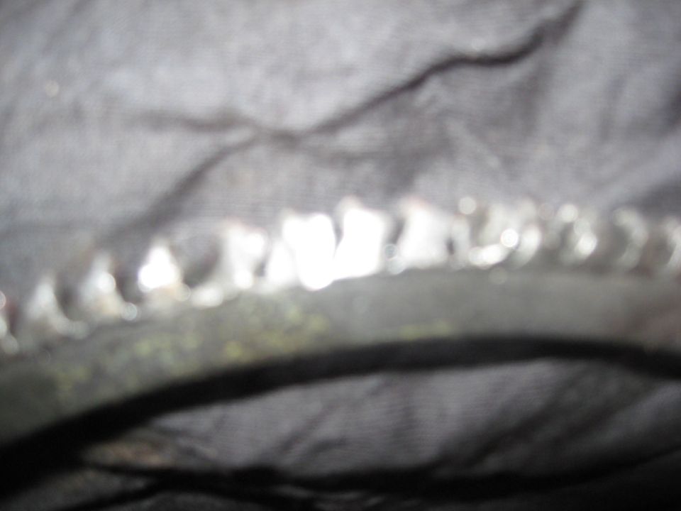 Blurry close-up of a toothed metal ring gear on dark fabric