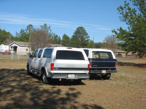 1978 Ford Bronco - Photo of a silver Ford crew-cab truck and a dark Ford Bronco parked outdoors, not a technical document.
