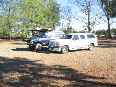 1978 Ford Bronco - Photo of a blue Ford Bronco and a white Ford crew-cab parked in a field, not a technical document.