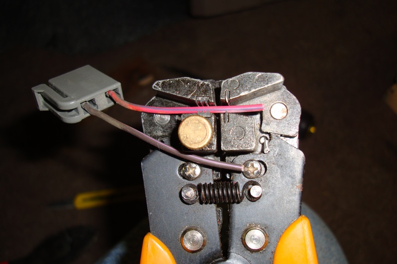 Wire stripper crimping red and gray wires into a gray connector