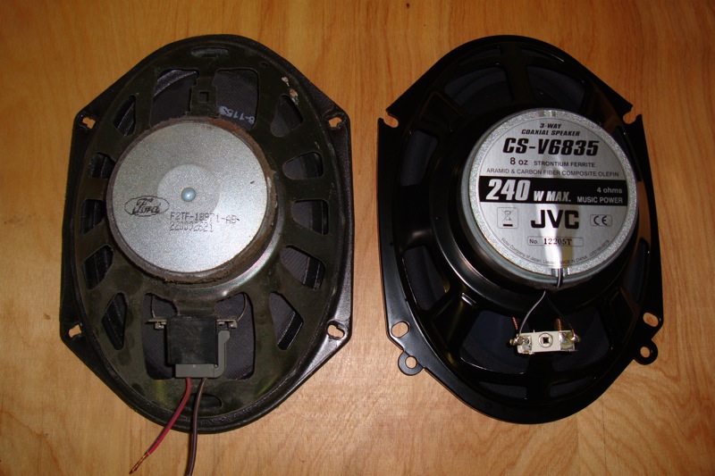 Ford OEM speaker beside a JVC CS-V6835 aftermarket speaker on a wood floor