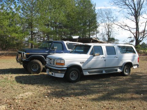1978 Ford Bronco - Photo of a white Ford crew-cab and a dark Ford Bronco parked outdoors, not a technical document.