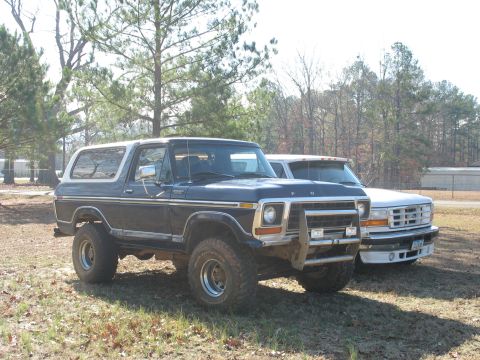 1978 Ford Bronco - Photo of a vintage dark Ford Bronco and a white Ford parked together, not a technical document.