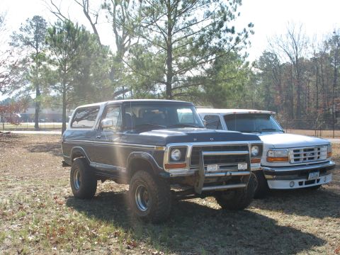 1978 Ford Bronco - Photo of a dark Ford Bronco and a white Ford crew-cab parked outdoors, not a technical document.