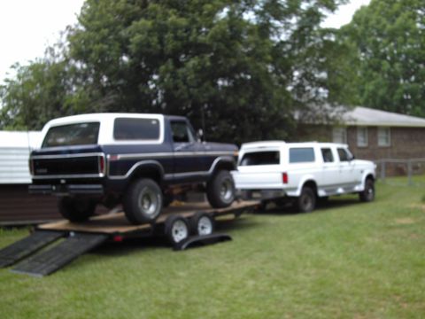 1978 Ford Bronco - 1978 Ford Bronco being transported on a trailer, towed by a white van.