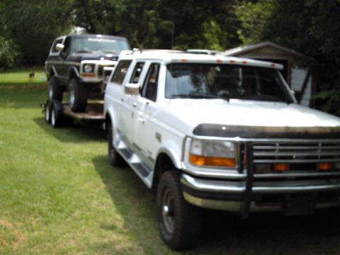 1978 Ford Bronco - A black 1978 Ford Bronco is transported on a trailer, towed by a white Ford SUV.