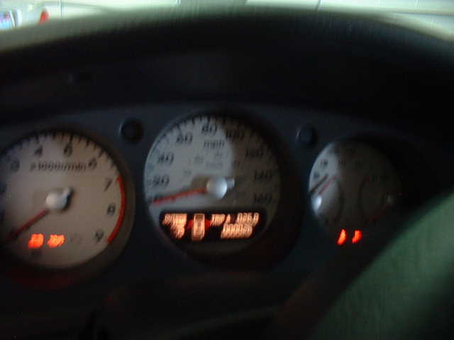 Blurry car instrument cluster with tachometer, speedometer, and illuminated warning lights