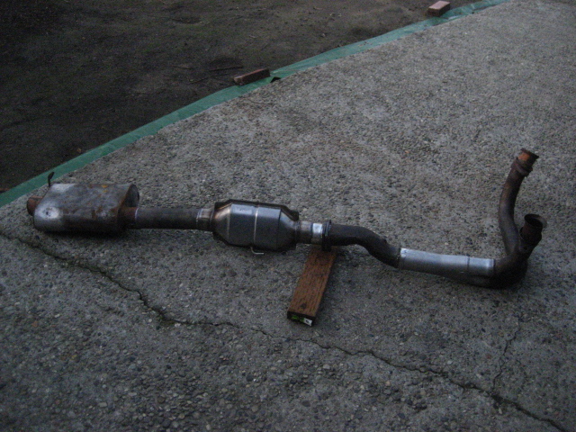 Used exhaust system with muffler, catalytic converter and pipes on concrete