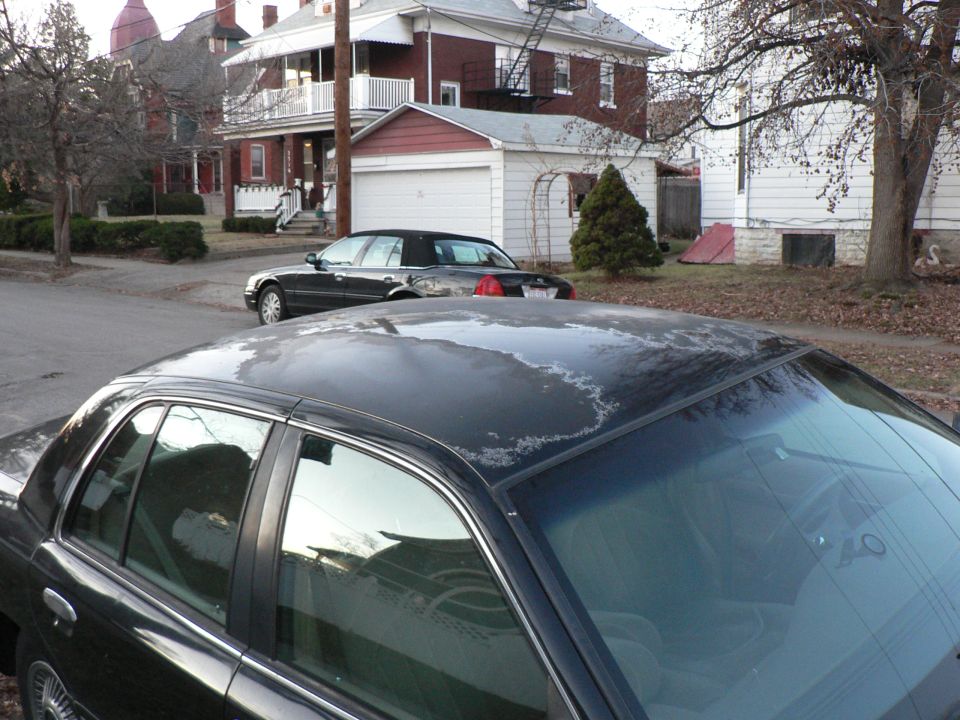 Dark green four-door sedan roof and windshield on a residential street