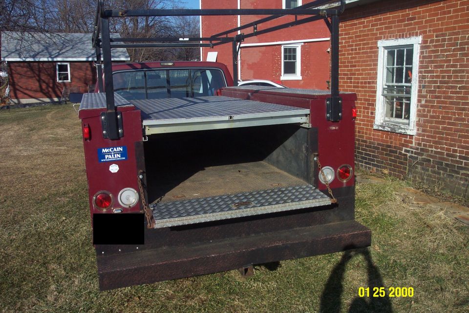 Rear view of a dark red Ford F-250 pickup truck with a utility bed and rack.