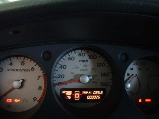 Illuminated car gauge cluster with tachometer, mph speedometer, and digital trip/odometer display.