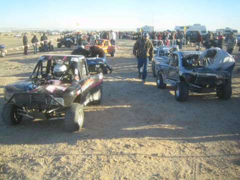 1990 Ford Bronco - Photograph of several off-road race vehicles staged near spectators at a desert race, not a technical document.