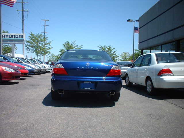 Rear view of blue Acura sedan in dealership lot with dual exhaust