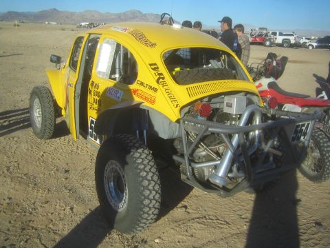 1990 Ford Bronco - Photograph of a yellow Baja Bug race car with exposed rear engine in a desert pit, not a technical document.