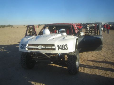1990 Ford Bronco - Photograph of white off-road race truck number 1483 in a desert staging area, not a technical document.