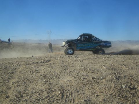1990 Ford Bronco - Photograph of black off-road race truck number 522 powering through dust on a desert course, not a technical document.