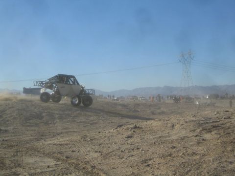 1990 Ford Bronco - Photograph of a single-seat off-road race buggy on a desert course near a transmission tower, not a technical document.