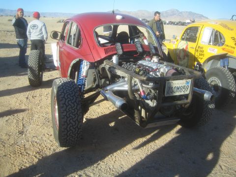 1990 Ford Bronco - Photograph of a red Baja Bug race car with exposed rear engine in a desert pit, not a technical document.