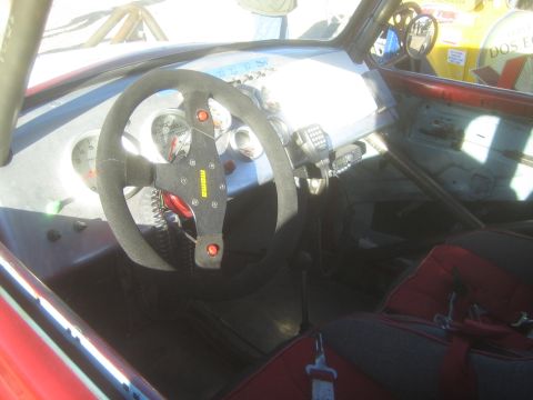 1990 Ford Bronco - Photograph of the cockpit interior of an off-road race car with steering wheel, gauges and harness, not a technical document.
