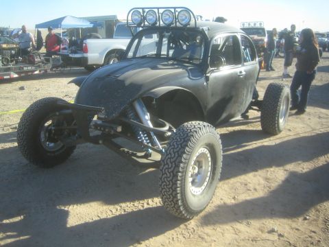 1990 Ford Bronco - Photo of a Baja Bug off-road race car parked in a desert staging area, not a technical document.