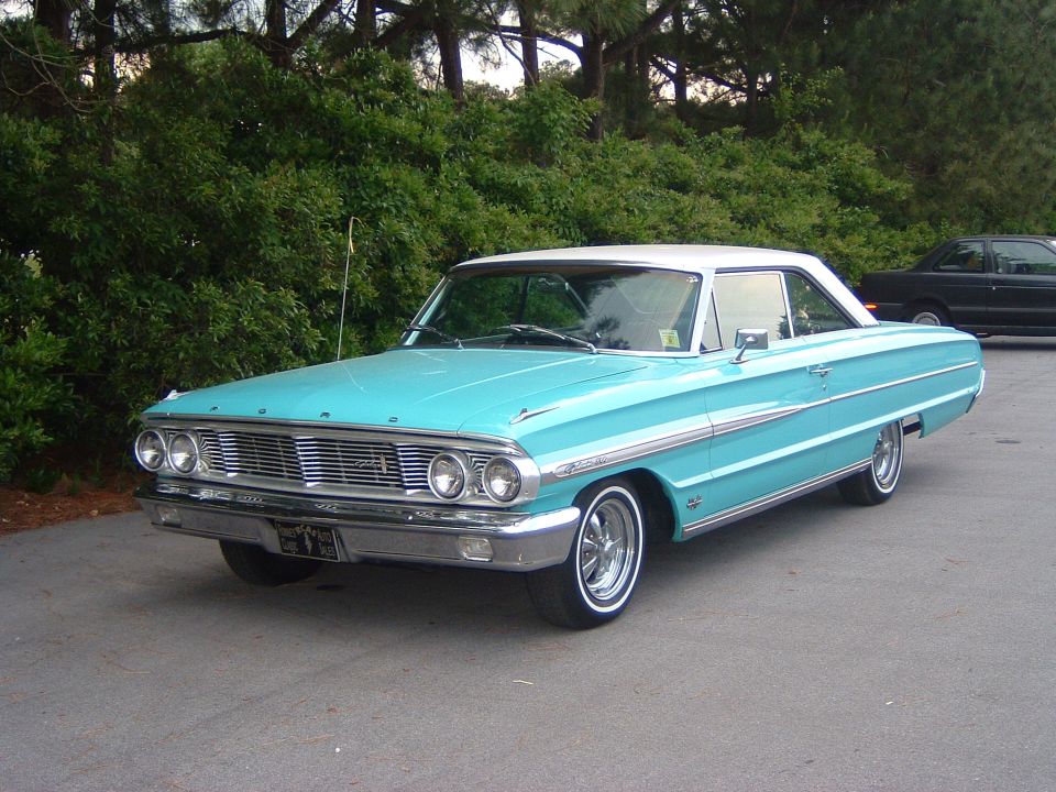 Turquoise 1964 Ford Galaxie 500 hardtop with white roof and whitewall tires, front three-quarter view