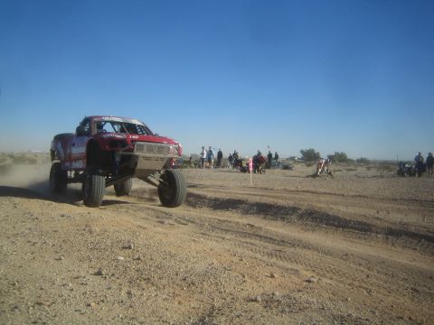1990 Ford Bronco - Photo of a desert race truck mid-jump on a dirt course, not a technical document.