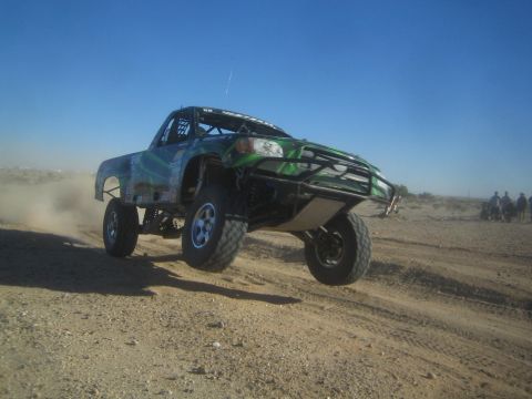 1990 Ford Bronco - Photo of an off-road race truck jumping on a desert course, not a technical document.