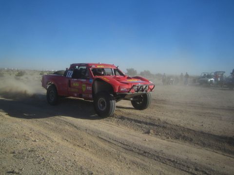 1990 Ford Bronco - Photo of a red off-road race truck on a dusty desert course, not a technical document.