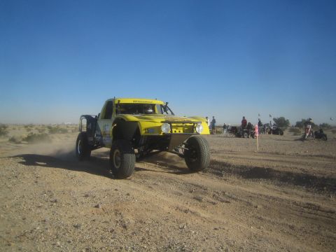 1990 Ford Bronco - Photo of a yellow off-road race truck on a desert course, not a technical document.