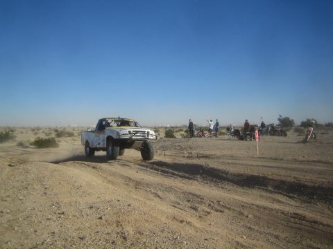 1990 Ford Bronco - Photo of a white off-road race truck on a desert course, not a technical document.