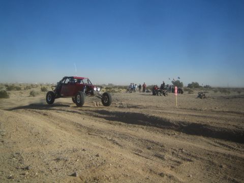 1990 Ford Bronco - Photo of a red off-road race buggy in the desert, not a technical document.