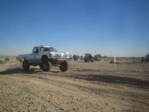 1990 Ford Bronco - Photo of a white off-road race truck on a desert course, not a technical document.