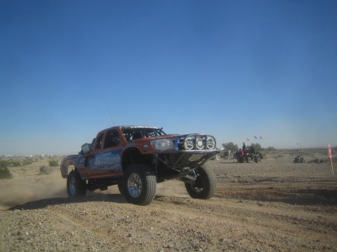1990 Ford Bronco - Photo of an off-road race truck on a desert course, not a technical document.