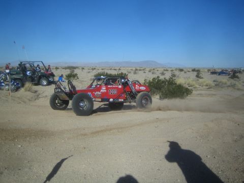 1990 Ford Bronco - Photo of a red off-road race buggy in the desert, not a technical document.
