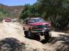 1996 Ford Bronco - 1996 Ford Bronco navigating an off-road trail with another vehicle in the background.