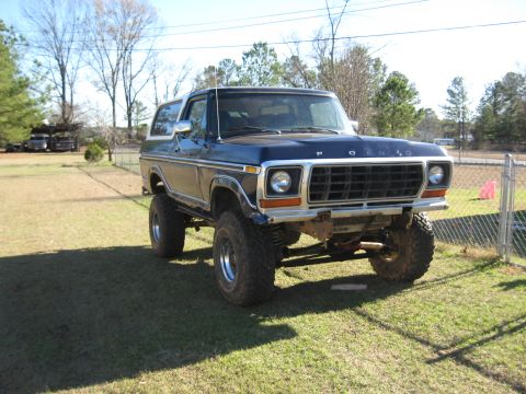 1978 Ford Bronco - Photograph of a lifted blue late-1970s Ford Bronco in a yard, not a technical document.