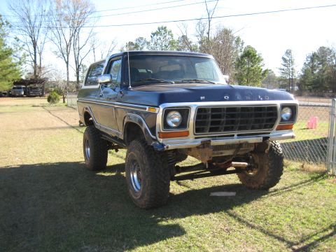 1978 Ford Bronco - Photograph of a lifted blue late-1970s Ford Bronco in a yard, not a technical document.