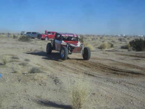 1990 Ford Bronco - Photograph of a red and white off-road race buggy in the desert, not a technical document.