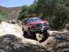 1996 Ford Bronco - This red SUV is tackling a challenging off-road path, with another vehicle following behind.