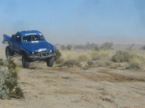 1990 Ford Bronco - Photograph of a blue off-road race truck in the desert, not a technical document.