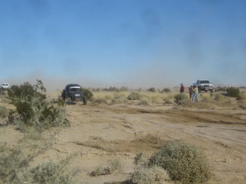 1990 Ford Bronco - Photograph of a dark off-road race buggy in the desert, not a technical document.