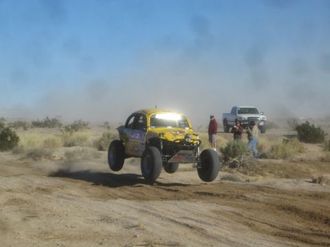 1990 Ford Bronco - Photograph of a yellow off-road race buggy in the desert, not a technical document.