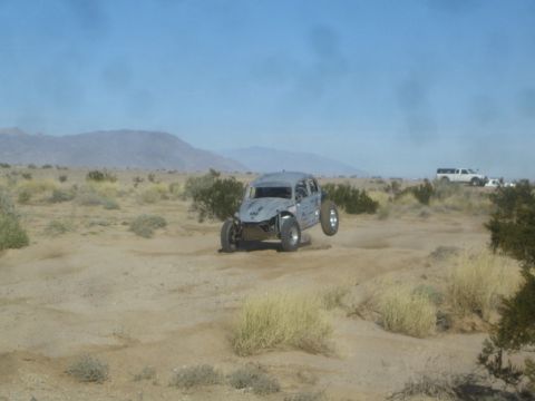 1990 Ford Bronco - Photograph of a gray off-road race buggy in the desert, not a technical document.